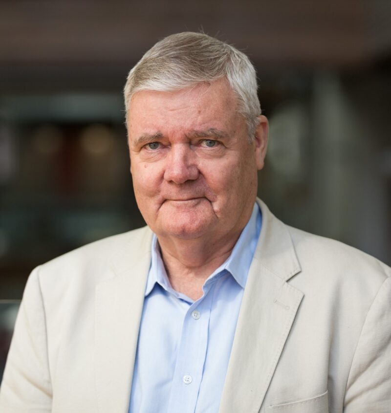 Jim Macnamara head and shoulders. Jim wears a light suit jacket and blue shirt