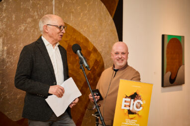 Kevin Ruck and Martin Flegg in front of a colourful artwork speaking at the launch of Exploring Internal Communication 5th edition